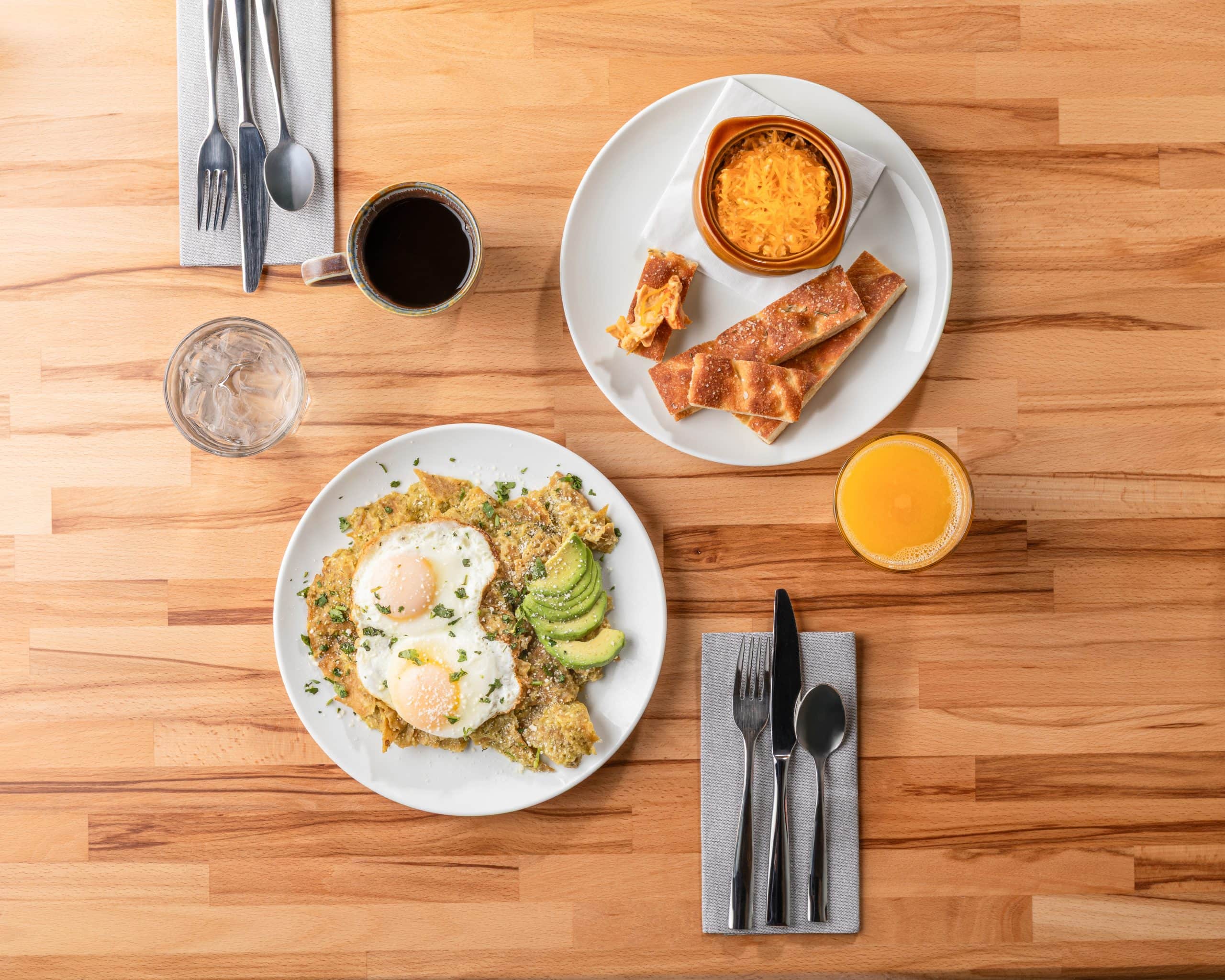 Breakfast plate with eggs, avocado, and side dishes on a wooden table.