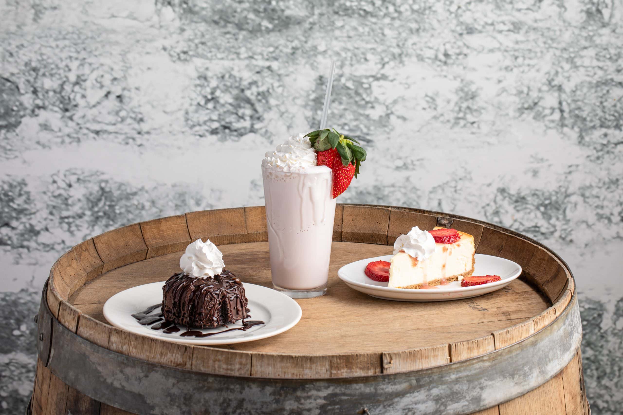 Assorted desserts and a milkshake on a wooden barrel table in Waukegan.
